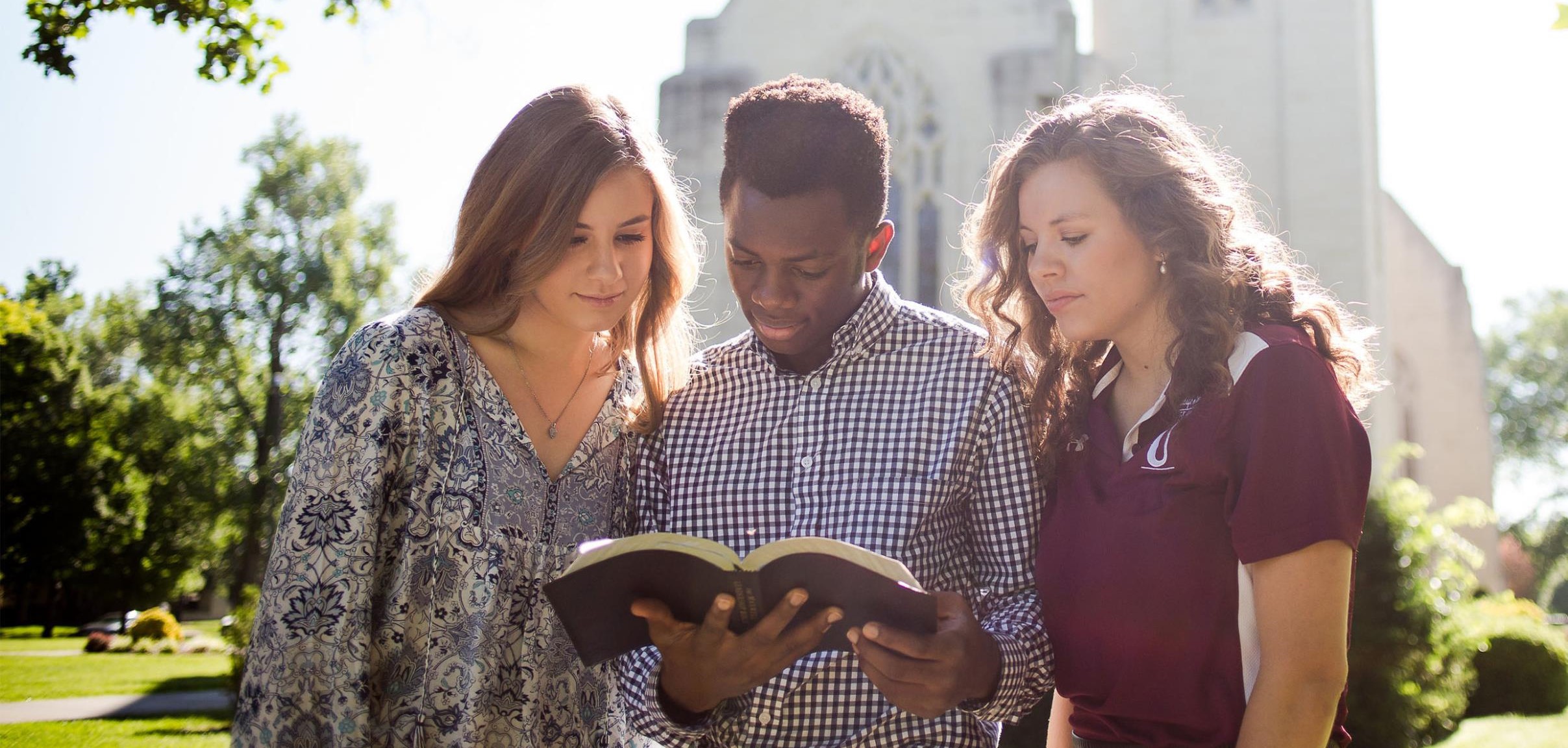 3 students reading the Bible outside of the chapel